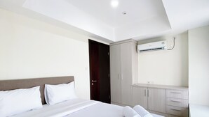 A hotel room with a bed, a wardrobe, and an air conditioning unit. - Well Furnished And Cozy 2Br Pollux Chadstone Apartment (Cikarang)