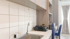 Μια κουζίνα με έναν ανοξείδωτο νεροχύτη, ένα μικρό μπουκάλι υγρό πιάτων και μια φορητή θερμάστρα πάνω στον πάγκο.