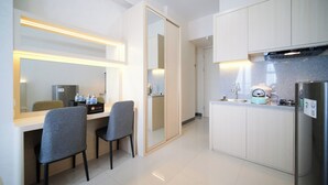A modern hotel room with a kitchenette, a dining area with two chairs, and a large mirror. - Nice And Modern Studio At Benson Supermall Mansion Apartment (Surabaya)