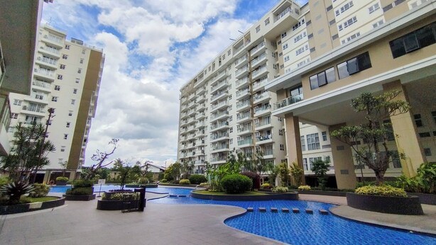 A residential building with multiple floors, balconies, and a swimming pool area with surrounding greenery. - Amazing 1Br Apartment Gateway Pasteur (Cimahi)