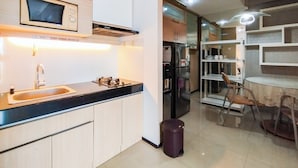 A modern kitchen with a built-in microwave, stainless steel appliances, and a dining area with a table and chairs. - Amazing 1Br Apartment Gateway Pasteur (Cimahi)