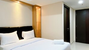 A neatly made bed with white linens, a wooden headboard, and a small nightstand with a lamp.