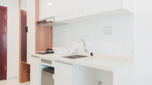 A modern kitchen with white cabinetry, a stainless steel sink, and a built-in dishwasher. - Restful And Homey Studio At Sky House Alam Sutera Apartment (Tangerang)