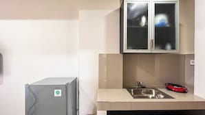 Een kleine keuken met een koelkast, een spoelbak en een kast erboven.