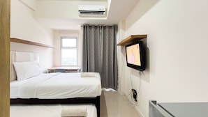 Een hotelkamer met een bed, een bureau, een televisie en een airconditioning.