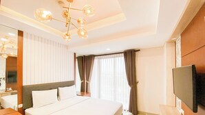 Una habitación de hotel con una cama grande, un televisor, un escritorio y una lámpara de araña moderna.