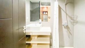 Un baño moderno con un espejo grande, un lavamanos y una ducha.