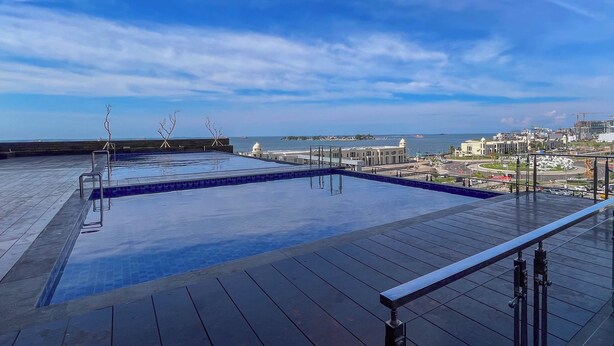 Una piscina a sfioro sul tetto con una vista chiara sullo skyline della città e sul mare.