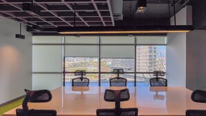 Una sala conferenze con un lungo tavolo, quattro sedie, ampie finestre e vista sulla città.