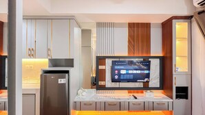 Una cucina moderna con frigorifero integrato, TV a schermo piatto montata a parete e un piano di lavoro in marmo.