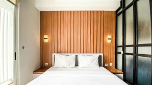 Ett hotellrum med en stor säng, en väggpanel i trä, två sängbord och ett fönster med persienner.