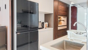 Apartemen Deluks | Dapur pribadi | Lemari es besar, microwave, kompor, dan meja makan