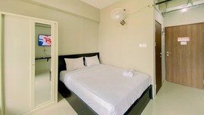 A bedroom with a bed, a wall-mounted TV, a ceiling fan, and a door with a sign. - Good Deal And Homey Studio At Royal Sentul Park Apartment (Bogor)