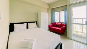 Une chambre d’hôtel avec un grand lit, un canapé rouge, une armoire et une fenêtre avec des rideaux.