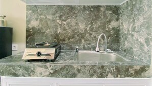 Une cuisine dotée d’un plan de travail en marbre, d’un évier et d’un chauffe-eau Rinnai.