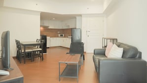 A modern living room with a dining area, a kitchen in the background, and a grey leather sofa. - Good Place 2Br Apartment At Sudirman Tower Condominium (Jakarta)