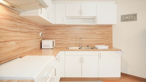 A modern kitchen with white cabinets, a wooden backsplash, a built-in microwave, and a stainless steel sink. - Good Place 2Br Apartment At Sudirman Tower Condominium (Jakarta)