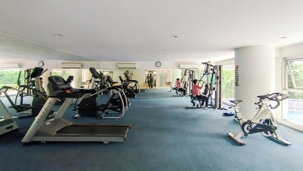 A gym with cardio machines, weight machines, and a mirrored wall. - Homey 1Br Apartment At Dago Suites (Bandung)