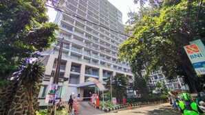 A multi-story hotel with a modern design, featuring balconies on each floor. - Homey 1Br Apartment At Dago Suites (Bandung)