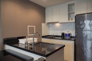A modern kitchen with a black countertop, stainless steel appliances, and white cabinetry.