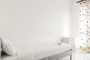 Una camera da letto minimalista con un letto, un comodino e una lampada da notte.