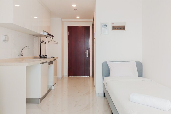 Una camera d'albergo con un letto, un angolo cottura e una porta che dà su un'altra stanza.