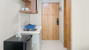 Une cuisine de taille réduite avec un réfrigérateur noir, un évier et des placards en bois.