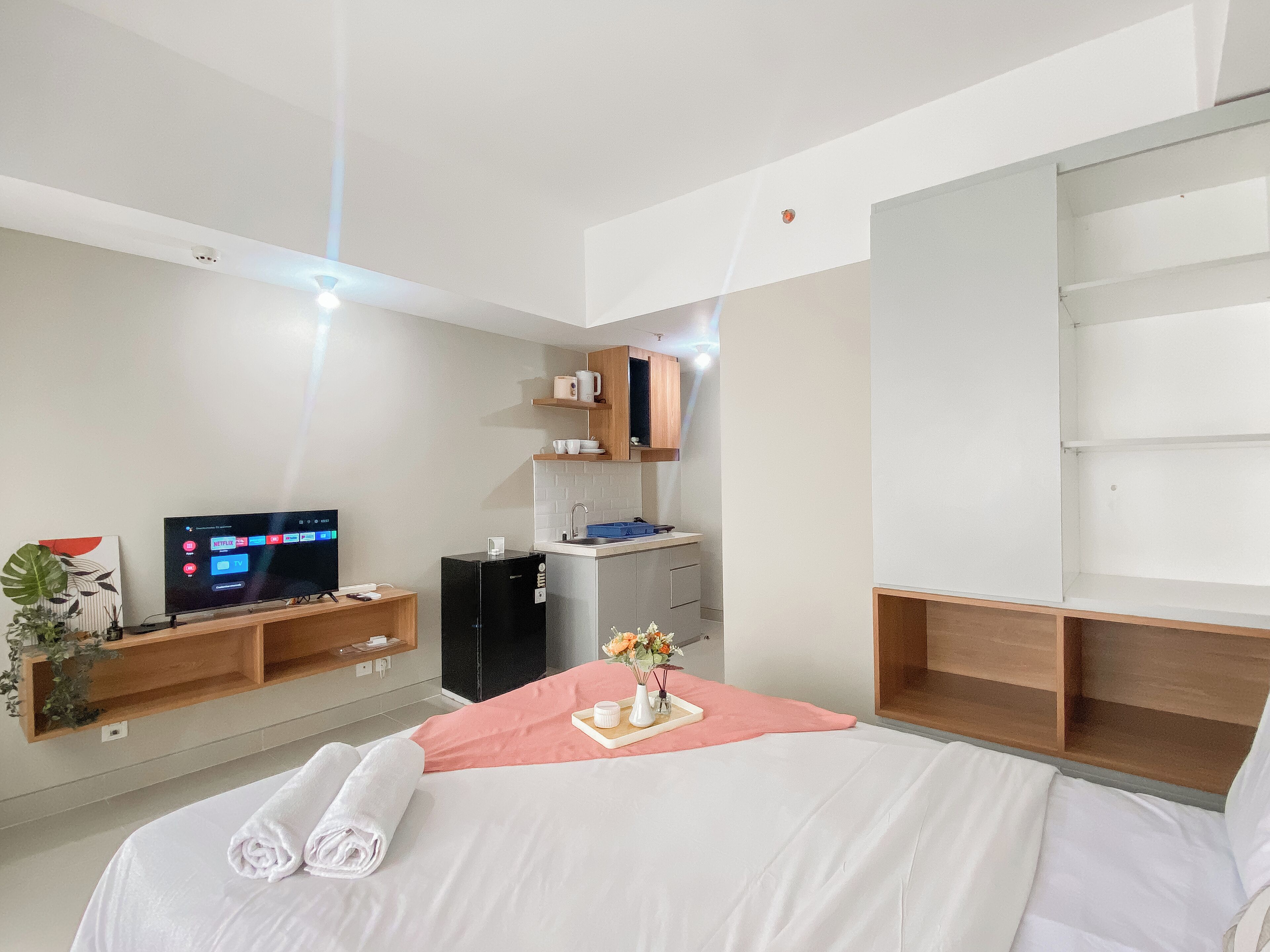 Une chambre d’hôtel équipée d’un lit, d’une télévision, d’un minibar, d’un bureau et d’un grand miroir.