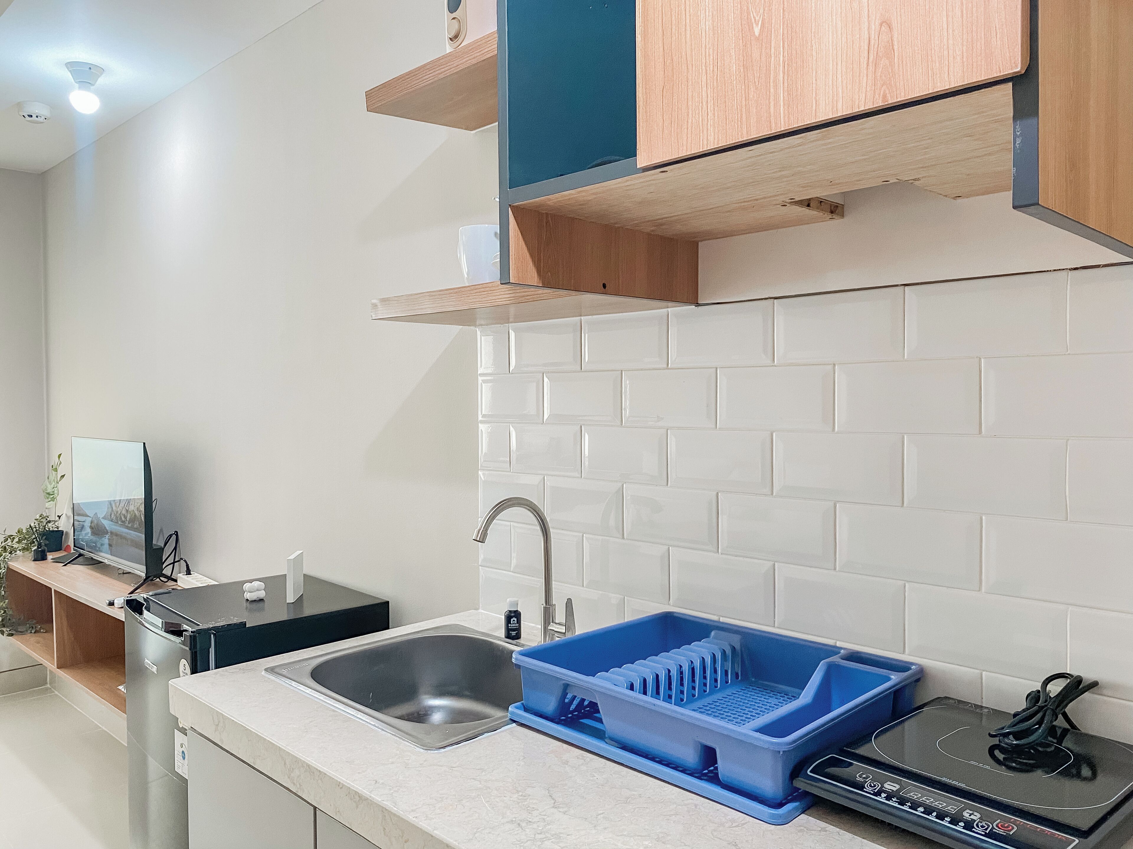 A modern kitchen with a stainless steel sink, a blue dish rack, and wooden cabinets.