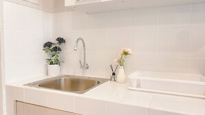 Una cocina moderna con armarios blancos, un lavamanos de acero inoxidable y una encimera blanca.