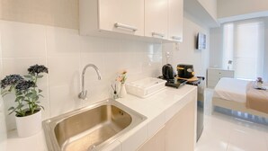 Cocina moderna con armarios blancos, pileta de acero inoxidable y una cafetera.