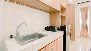 A kitchen with a double sink, wooden cabinets, and a built-in stove. - Cozy And Homey Studio At Springlake Summarecon Bekasi Apartment (Bekasi)