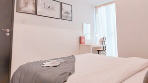Une chambre à coucher avec un lit, un bureau et une chaise. Des tableaux encadrés ornent le mur.