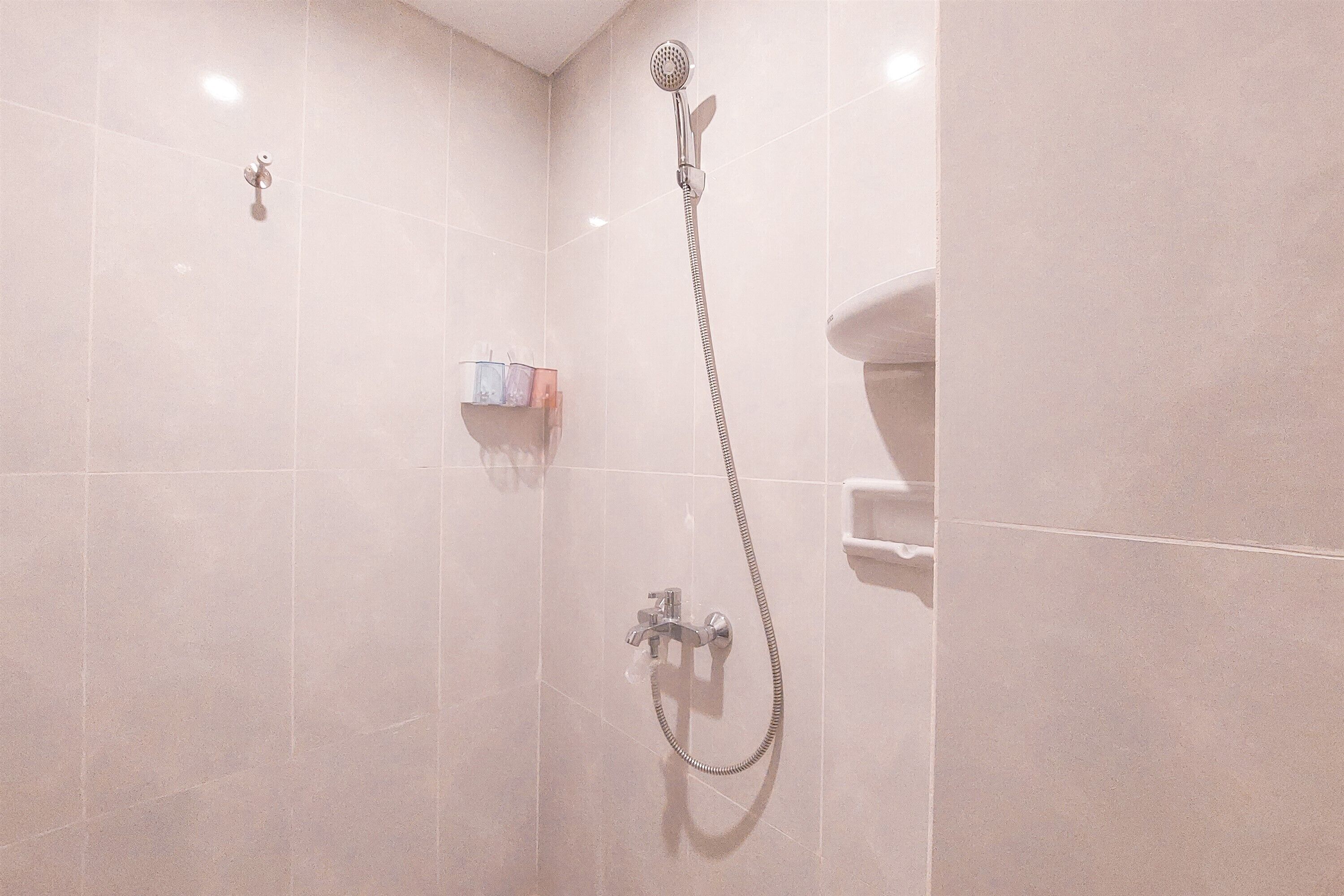 A shower with a handheld showerhead and a wall-mounted faucet.