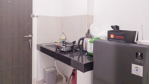 A compact kitchen with a sink, stove, and a travelio branded appliance. - Homey And Cozy Studio At Serpong Garden Apartment (Cisauk)