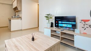 Un salon moderne doté d’un téléviseur à écran plat, d’une plante en pot et d’un aménagement minimaliste.