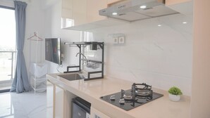 A modern kitchen with a built-in stove, a sink, and a small potted plant. - Comfy And Best Deal Studio Sky House Bsd Apartment Near Aeon (Pagedangan)