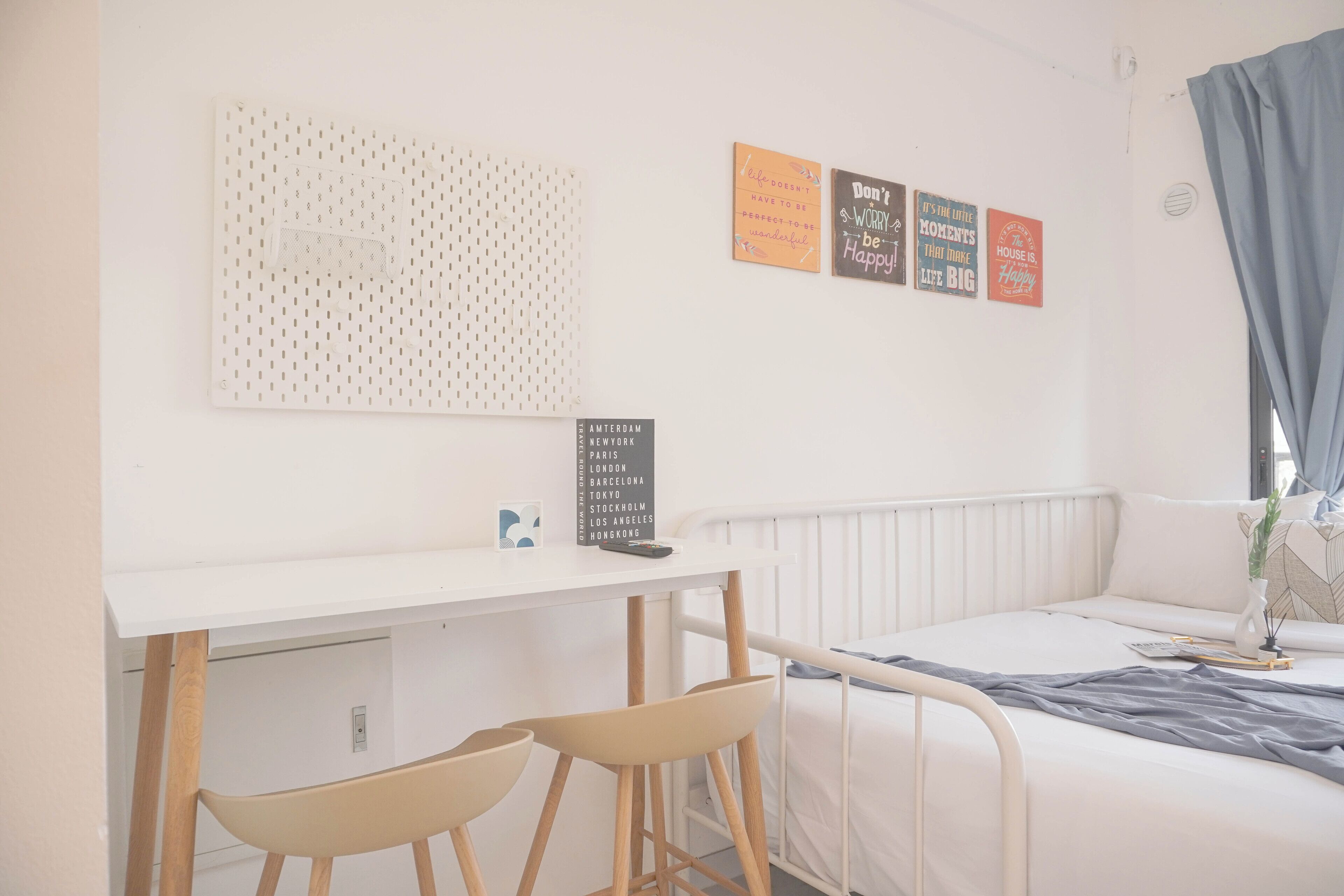 A bedroom with a bed, a desk, two chairs, and motivational wall art.
