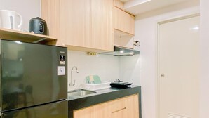 A compact kitchen with a refrigerator, sink, and wooden cabinets. - Modern And Serene Look 2Br Tokyo Riverside Pik 2 Apartment (Teluknaga)