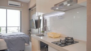 A modern kitchen with a gas stove, sink, and a flat-screen TV mounted above the counter. - Comfort And Good Place Studio At Sky House Bsd Apartment (Pagedangan)
