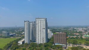A high-rise residential building with multiple balconies, surrounded by greenery and other buildings. - Comfort And Good Place Studio At Sky House Bsd Apartment (Pagedangan)