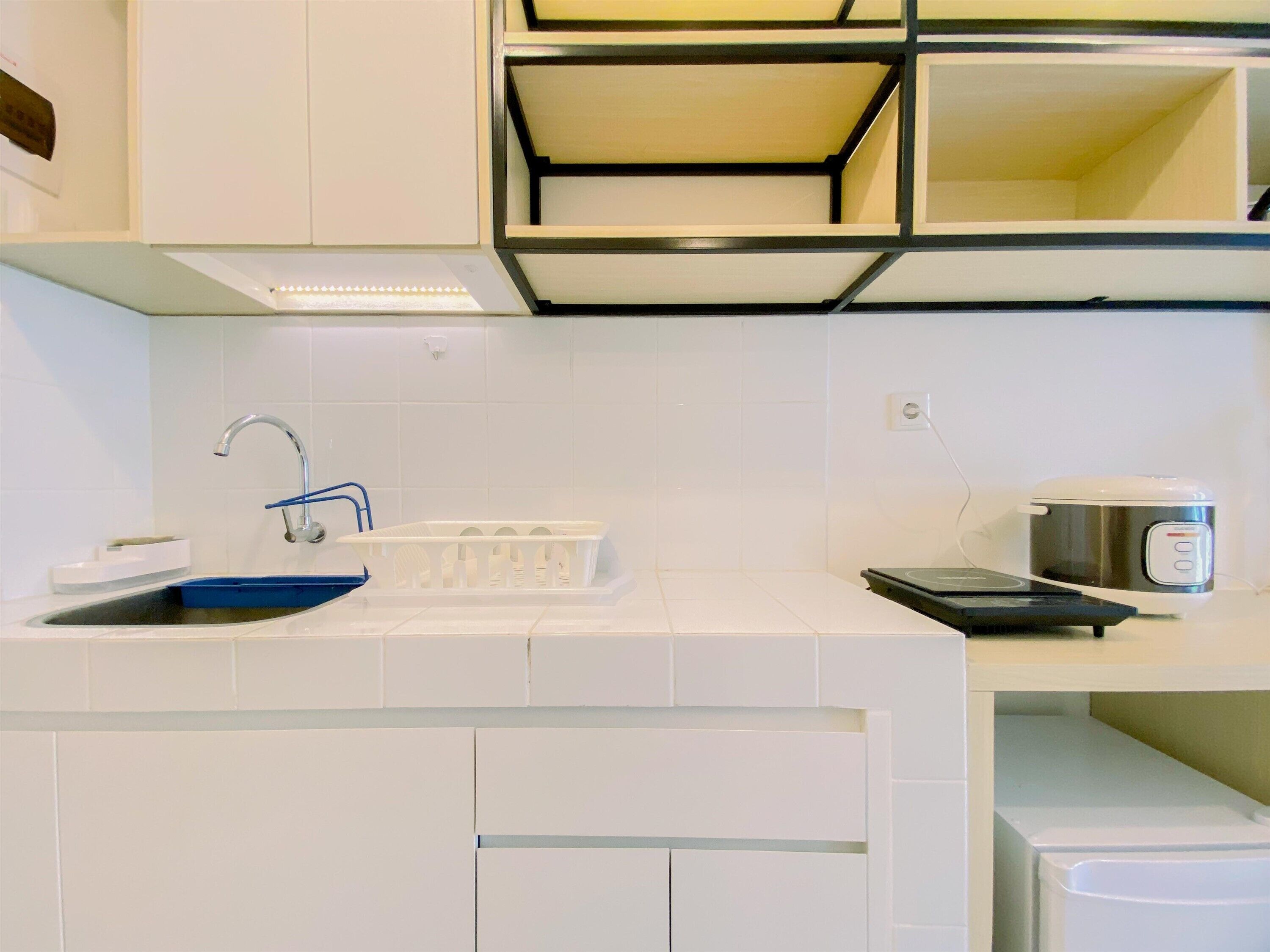 Una cocina moderna con muebles blancos, un lavamanos de acero inoxidable y un horno empotrado.