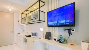 A modern kitchen with a built-in TV, a coffee maker, and a laptop on the counter. - Comfy Studio At Tokyo Riverside Pik 2 Apartment (Teluknaga)