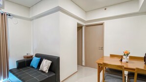 Una sala moderna con un sofá negro, una mesa de comedor de madera y una mesita auxiliar.