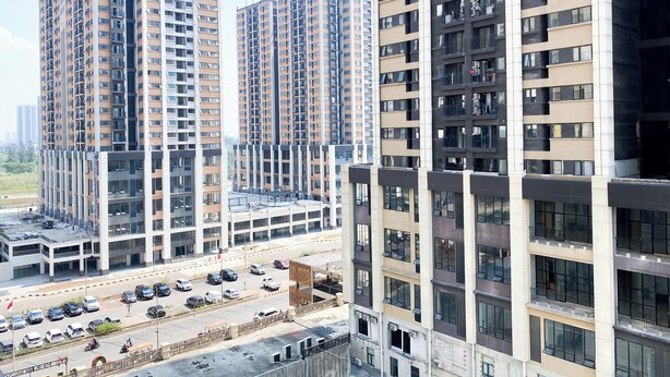 Un edificio residencial de gran altura con varios pisos, una zona de estacionamiento al frente y una vista despejada del entorno urbano.
