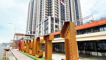 A modern urban street with high-rise buildings, a pedestrian walkway, and bollards along the road.