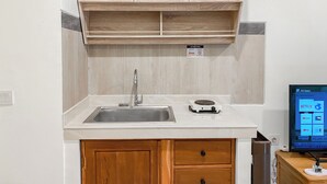 Una cocina con armarios de madera, un lavamanos de acero inoxidable y un electrodoméstico sobre la encimera.