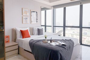 A modern hotel room with a large bed, a nightstand, a view of the city through large windows, and two framed inspirational quotes on the wall. - Good Place And Comfy Studio Apartment At The Smith Alam Sutera (Tangerang)