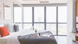 A modern bedroom with a large bed, city view, and a desk with a computer. - Good Place And Comfy Studio Apartment At The Smith Alam Sutera (Tangerang)