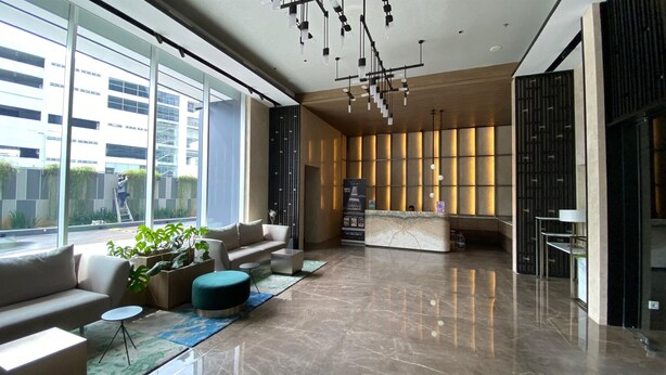 A modern lobby with a reception desk, seating area, and large windows offering views of the city. - Good Place And Comfy Studio Apartment At The Smith Alam Sutera (Tangerang)
